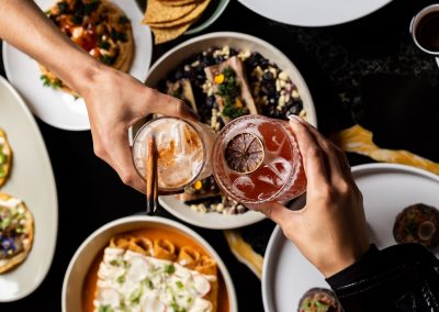 Cheers, clinking glasses with background of food plates